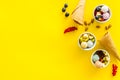 Gelato, waffle cone, berries, chocolate, hazelnut on yellow background top view copyspace