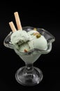 Summer dessert and refreshing treat concept with green pistachio ice cream and sparse pistachios isolated on black background with Royalty Free Stock Photo