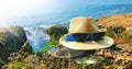 Summer details. A hat and sunglasses on a rock up close and blue sea in the background.