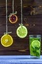 Summer drink. Hanging on threads slices of lemon, orange and lime. Summer fresh Mojito with ice. Royalty Free Stock Photo