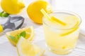 Summer drink of lemon, or lemonade, with mint leaves and hand juicer on white wooden table