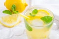 Summer drink of lemon and mint, or lemonade, with ice cubes on white wooden table