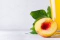 Summer drink - peach juice with leaves and fleshy slice nectarine closeup on soft light white wood background. Royalty Free Stock Photo