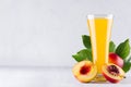 Summer drink - peach juice and red ripe nectarines with leaves and fleshy slice on soft light white wood background. Royalty Free Stock Photo