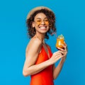 Summer Drink. Positive african woman enjoying colorful fruit cocktail on blue background