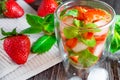 Summer drink of strawberries and mint with ice cubes on dark wooden table