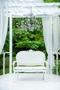 Summer elegant elegant gazebo in the lush gardens. Exquisite classic sofa gazebo Royalty Free Stock Photo