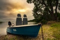 summer evening coastal walk. metal fishing or pleasure boat on the grassy shore of a large lake under a cloudy sky with a warm