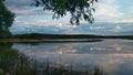 Summer evening at lake with dramatic sky and reflection in water and grass on foreground