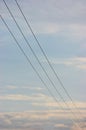 Summer evening sky background, vertical bright blue skyscape copy space, three power line cable wires, pink pastel clouds cloudine