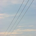 Summer evening sky background, vertical bright blue skyscape copy space, three power line cable wires, pink pastel clouds Royalty Free Stock Photo