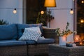 Evening on the terrace of beautiful suburban house with patio with wicker furniture and lights Royalty Free Stock Photo