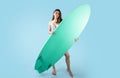 Summer extreme sport. Young lady in swimsuit posing with surfing board, enjoying summertime, pastel blue background Royalty Free Stock Photo