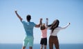 Summer family. Back view of happy young family walking on beach. Child with parents holding hands. Full length poeple. Royalty Free Stock Photo