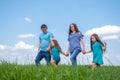 Summer family dad, mom and two children walking on green grass against blue sky. Happy caucasian parents with two Royalty Free Stock Photo