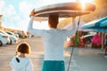 Summer family vacation. Father and daughter are walking along the beach. Man holding a sup board and girl holds a paddle. Back Royalty Free Stock Photo
