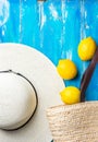 Summer fashion background. Straw hat wicker handwoven beach bag fresh lemons on blue wood. Travel vacation concept. Provence style Royalty Free Stock Photo