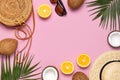 Summer fashion flat lay. Round trendy rattan bag straw hat sunglasses tropical palm leaves coconut orange on pink background. Top