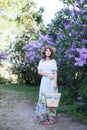 Summer fashion portrait of stunning woman walking in the blooming lilac garden. Wearing long vintage dress. Romantic mood. Secret Royalty Free Stock Photo