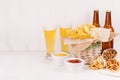 Summer fast food - different crunchy snacks, two lager beer in glass and brown bottles on soft white wood board.