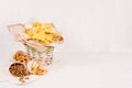 Summer fast food - different crunchy snacks in wicker rustic basket and craft paper cornet on soft white wood board.