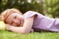 Summer is finally here. A smiling girl lying in the grass outside. Royalty Free Stock Photo