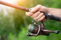 Summer fishing on the lake, a man`s hand holds a fishing rod, close-up Royalty Free Stock Photo