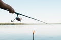 Summer fishing sport, hobby, leisure and recreation concept. Close-up of caucasian male fisherman holding spinning rod outdoors. Royalty Free Stock Photo