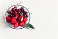 summer flat lay. fresh cherries and strawberries in stylish glass bowl on white rustic wooden background. ripe juicy red berries Royalty Free Stock Photo