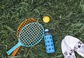 Summer flat lay on green grass with rackets and ball, glass bottle of water and summer white shoes Royalty Free Stock Photo