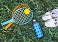 Summer flat lay on green grass with rackets and ball, glass bottle of water and summer white shoes Royalty Free Stock Photo