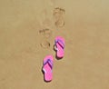 Summer flip flops on the beach with footsteps on sand Royalty Free Stock Photo