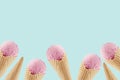 Summer food decorative border of delicious pink ice cream in crisp waffle cones on green background.