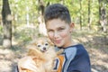 In summer  in the forest  a boy holds a small red dog in his arms Royalty Free Stock Photo