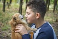 In summer  in the forest  a boy holds a small red dog in his arms Royalty Free Stock Photo