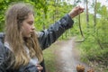 In summer in the forest on a bright sunny day agirl holds a spindle lizard without legs in his hand