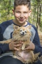 In summer in the forest a boy holds a small red dog in his arms Royalty Free Stock Photo