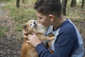 In summer  in the forest  a boy holds a small red dog in his arms Royalty Free Stock Photo
