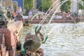 Summer fountain made of bronze geese. People are resting near the fountain.