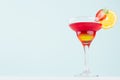 Summer fresh alcohol cocktail with red and yellow liquor, orange slice, strawberry on soft light white and pastel green. Royalty Free Stock Photo