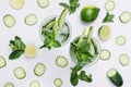 Summer fresh background - cold natural refreshing cocktail with slices cucumber, lime, mint, ice, straw on white wood plank. Royalty Free Stock Photo