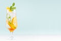 Summer fresh cold cocktail with oranges, green mint, ice, straw on soft light pastel green background and white wood table. Royalty Free Stock Photo