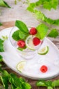 Summer fresh drink. Raspberry mint alcohol cocktail, slice of lime, ice cubes and raspberry on a natural wooden surface, Outdoor. Royalty Free Stock Photo