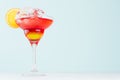 Summer fresh fruit layered red, yellow sunrise cocktail with orange slice, ice cubes in wineglass on pastel green background. Royalty Free Stock Photo