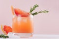 Summer fresh homemade grapefruit lemonade with ice cubes and rosemary closeup on light pink background. Royalty Free Stock Photo