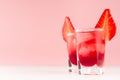 Summer fresh red cocktails in shot glasses with ice cubes, strawberry slice on white wood table and pastel pink wall, copy space. Royalty Free Stock Photo