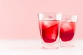 Summer fresh red strawberry drinks with ice cubes in two shot glasses on fashion pastel pink color background and white wood table Royalty Free Stock Photo