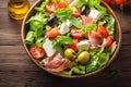 Summer freshness Mediterranean salad with lettuce, olives, tomatoes, prosciutto, and cheese