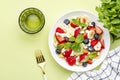Summer fruit and berry salad with feta cheese, fresh strawberries, blueberries, banana, kiwi, orange and mint, green background, Royalty Free Stock Photo