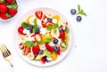 Summer fruit and berry salad with fresh strawberries, blueberries, banana, cottage cheese and mint on white table background, top Royalty Free Stock Photo
